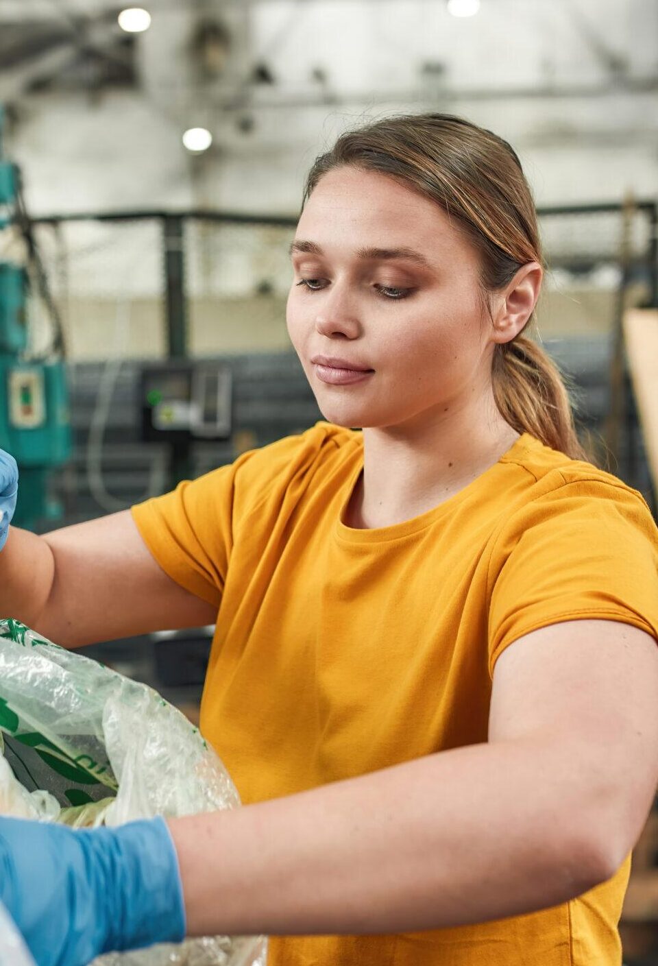 Young girl putting bottles into plastic bag on waste station