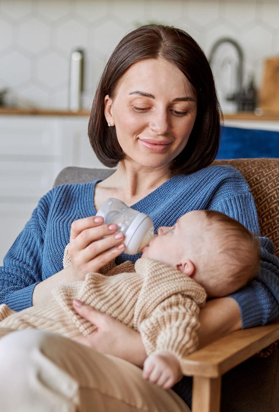 Mother feeding newborn baby from bottle with milk